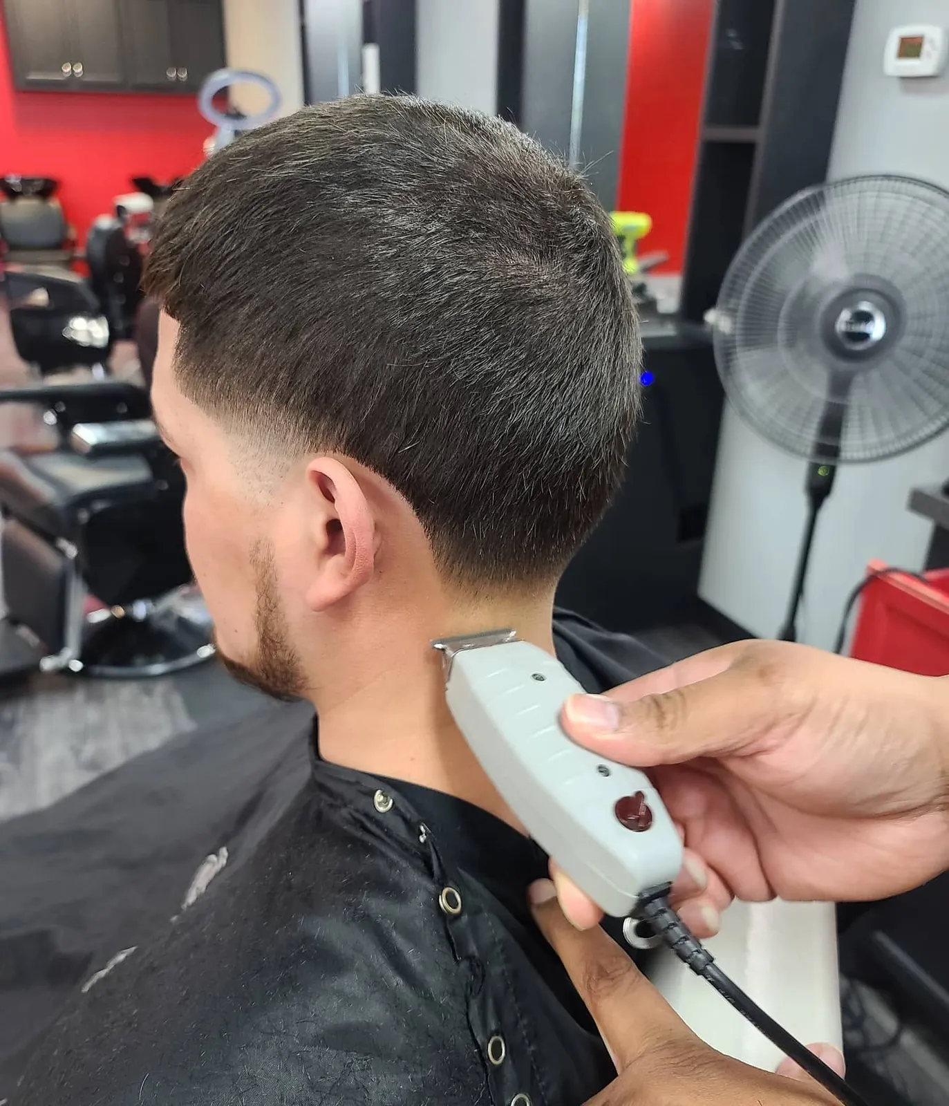 A Scissorhands barber finishing a low taper at the neckline