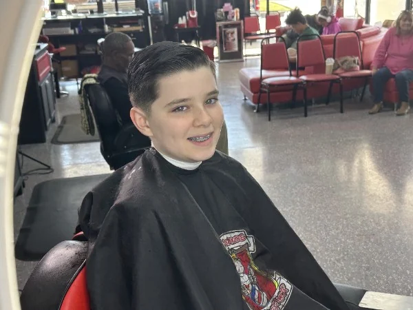 The same client smiling after a short slick-back cut